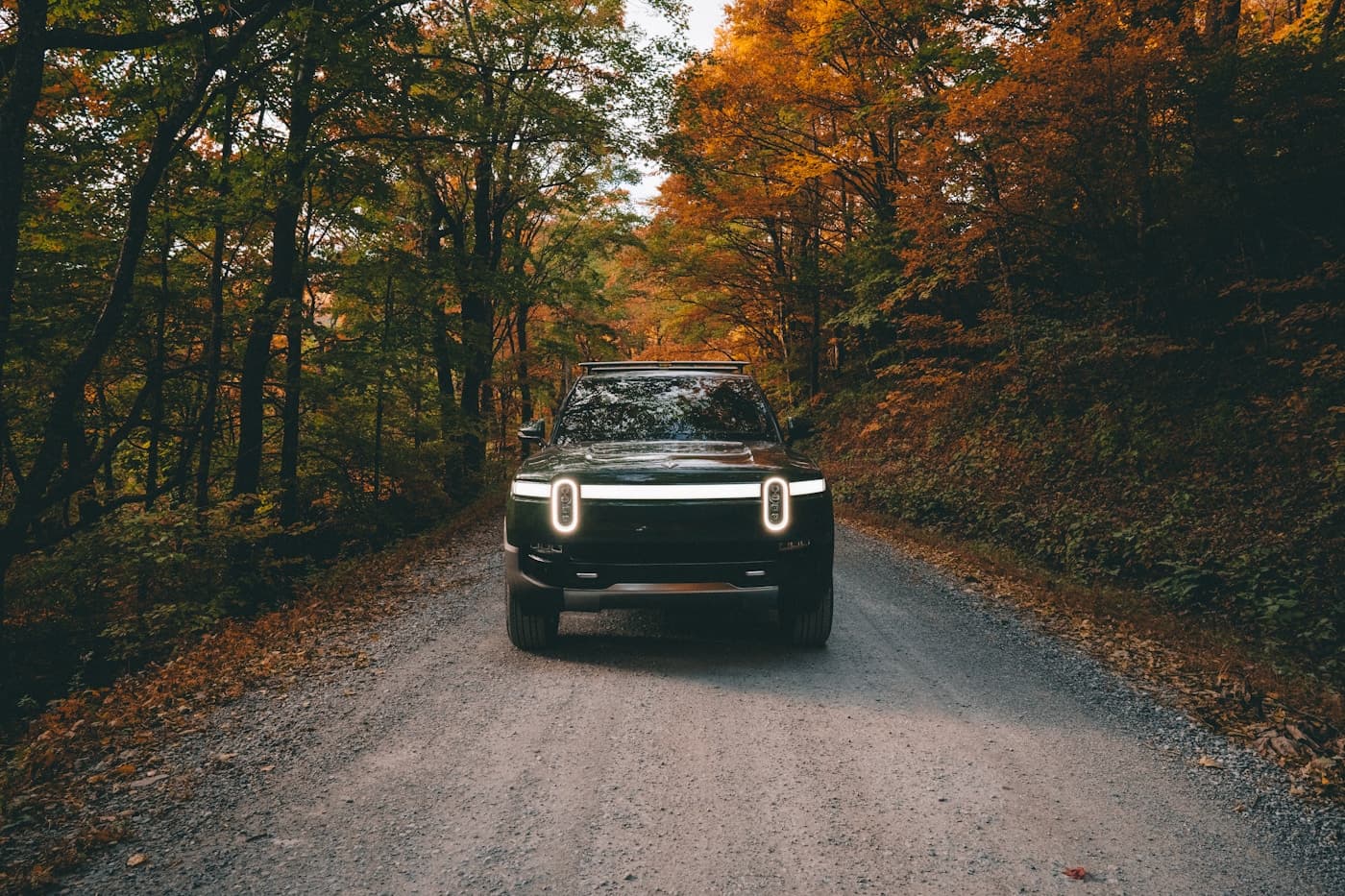 Forest Green Rivian R1T driving on a gravel road